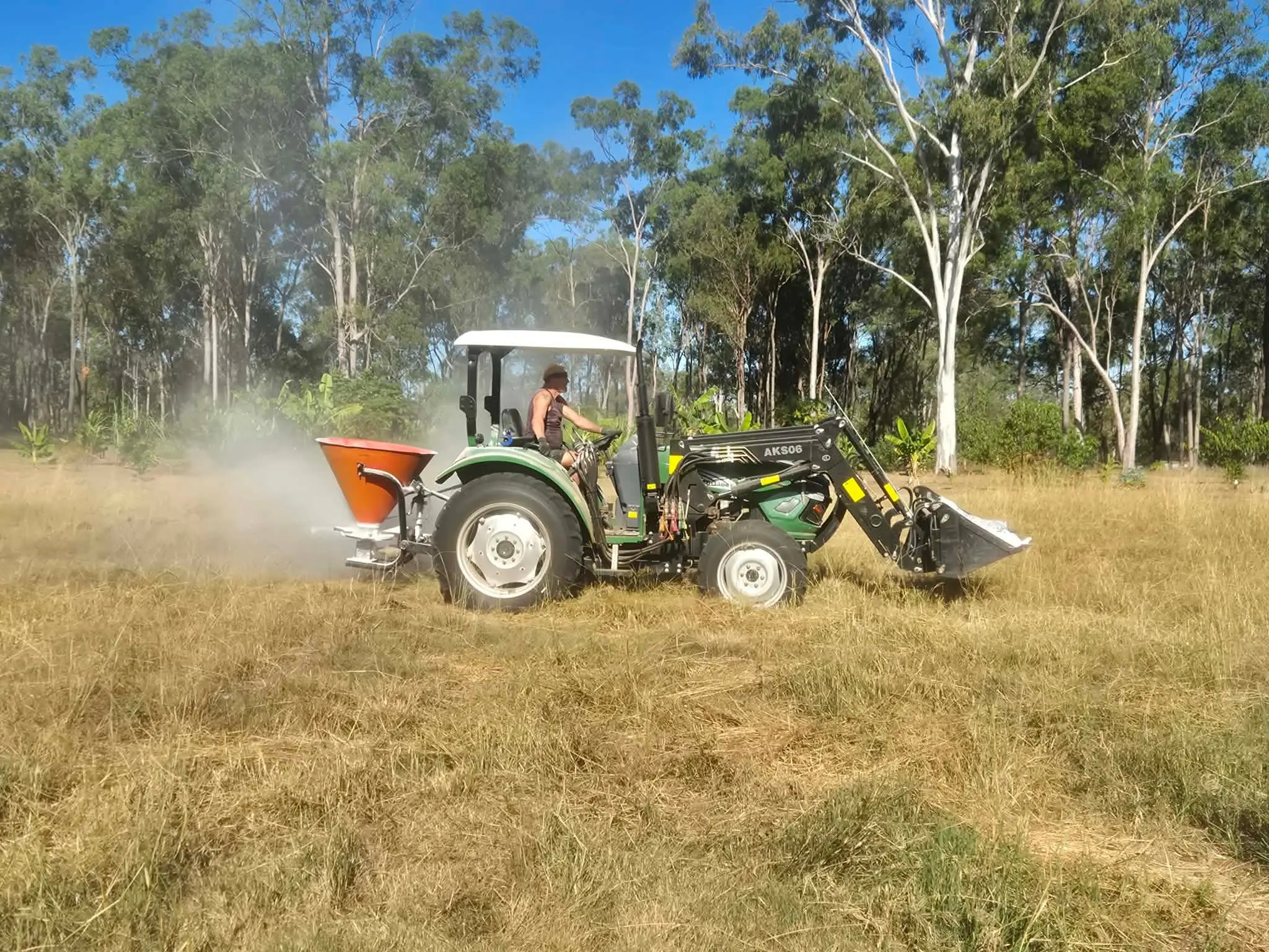 Ian on the tractor, spreading lime across a dry paddock